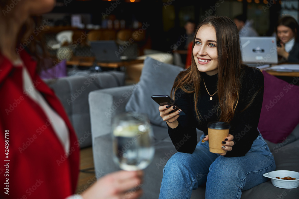 Charming young woman using cellphone and talking with colleague Charming young woman using cellphone and talking with colleague