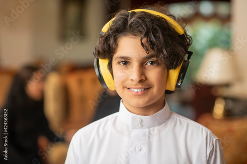 Young Arabian boy listening to music on headphones at home photo