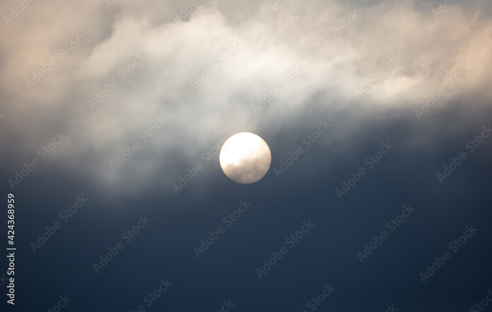Obraz premium The sun shines behind the clouds during