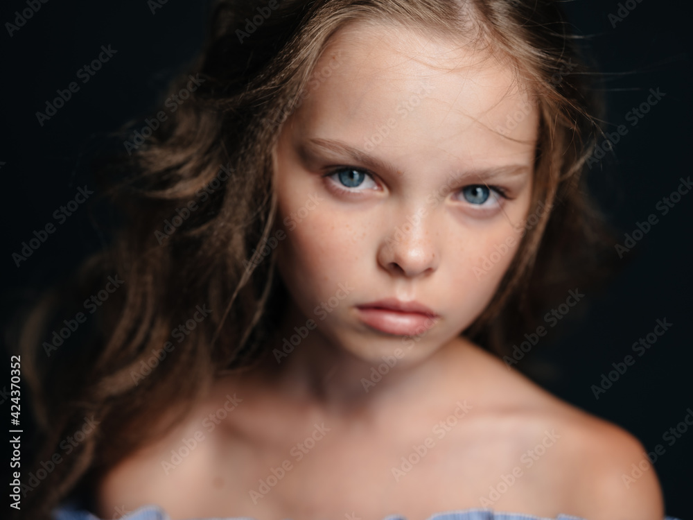 A beautiful blue-eyed girl with bare shoulders on a dark background and curly hair A beautiful blue-eyed girl with bare shoulders on a dark background and curly hair