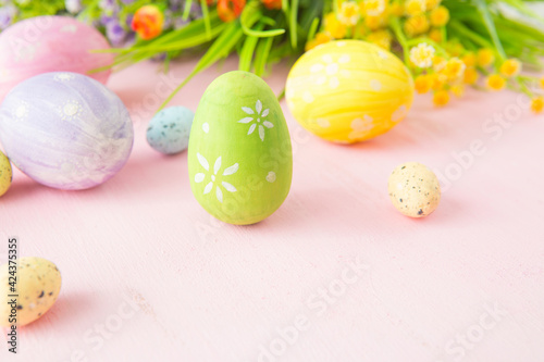 Easter eggs with wild flowers on a wooden pink table background