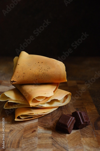 crepes pancake in a wooden board against dark background