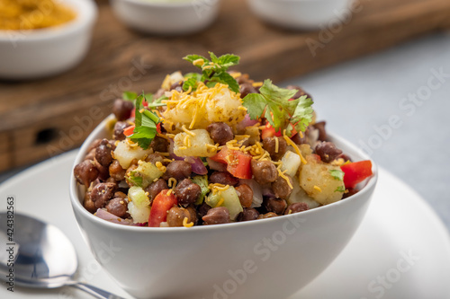 black gram or kala chana chaat with boiled potato, onion, tomato with a dash of lemon juice served on a white bowl
