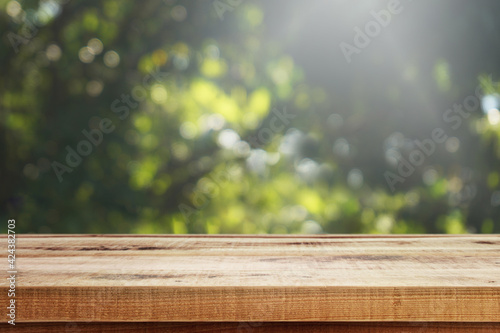Wooden table and green blurred nature background for product.