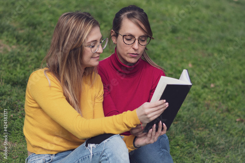 Two women enjoying reading a book in a park