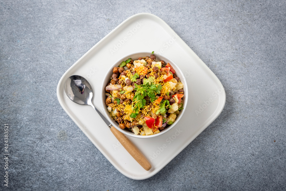 black gram or kala chana chaat with boiled potato, onion, tomato with a dash of lemon juice served on a white bowl