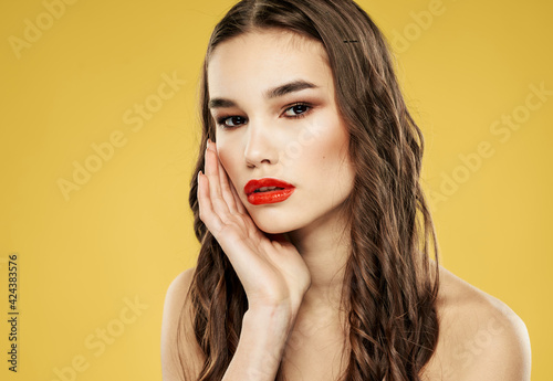 Brunette woman with red lips on a yellow background and makeup with eyeshadow