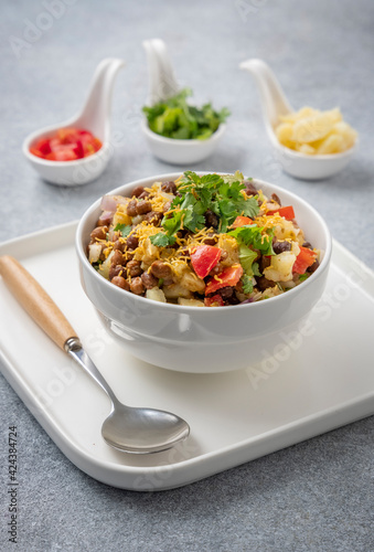 black gram or kala chana chaat with boiled potato, onion, tomato with a dash of lemon juice served on a white bowl