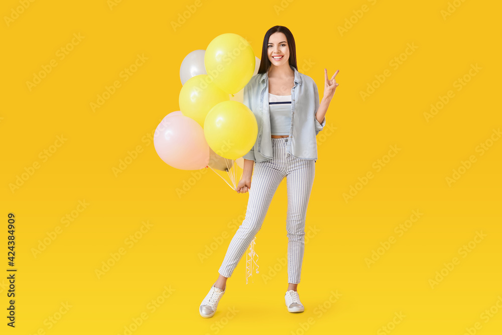 Beautiful young woman with balloons showing victory gesture on color background Beautiful young woman with balloons showing victory gesture on color background
