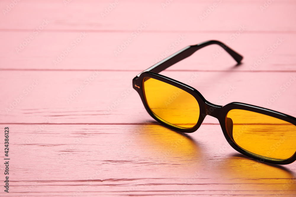 Stylish sunglasses on color wooden background, closeup Stylish sunglasses on color wooden background, closeup
