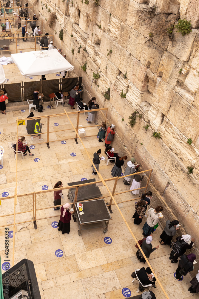 Obraz premium Jews pray on the women side of the Western Wall. View from the stairs leading to the Maghreb Gate of the Temple Mount, near the Western Wall, in the old city of Jerusalem, Israel