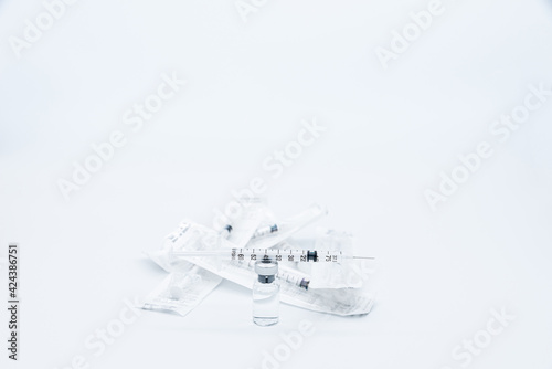 Dose of vaccine against Covid-19 Corona Virus prepared in the syringe placed on the bottle near a group of syringes still packed  isolated on white background.