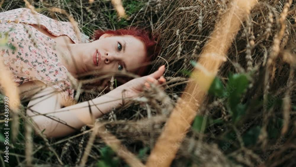 Close-up face of beautiful girl lying on the grass. Young woman with long hair on nature. Freedom. Countryside. Beauty and health