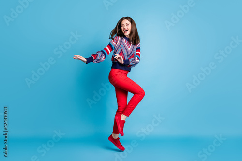 Full length profile side photo of young positive girl happy smile have fun jump up isolated over blue color background