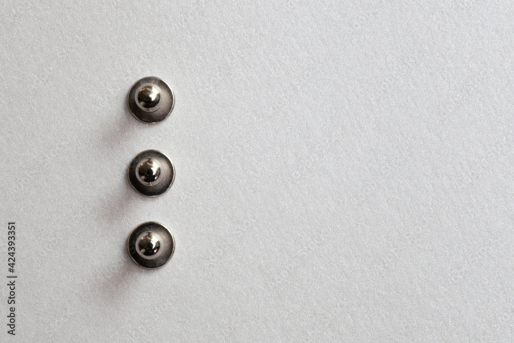 minimalism close-up three grommet, rivet, snap, button on the paper silver background. minimalism close-up three grommet, rivet, snap, button on the paper silver background.