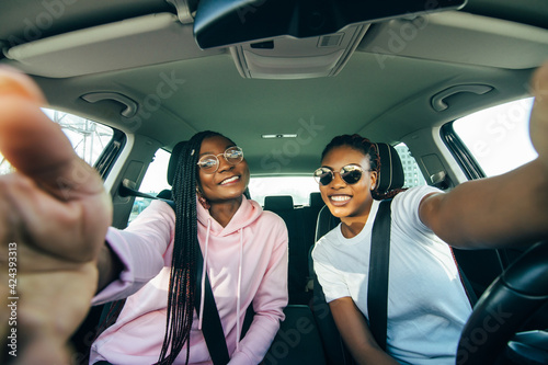 Two african woman making selfie in auto.Woman sitting inside, smiling, one woman holding phone. Female customers happy because of purchasing new auto. © F8  \ Suport Ukraine