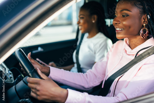 Two beautiful and pretty african women driving in car of their dream. Two women smiling because of successful purchase of automobile in car dealership.
