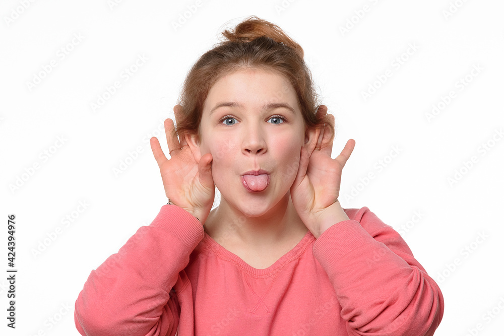 Close-up portrait of cheerful young girl making funny face and showing her tongue. White background Close-up portrait of cheerful young girl making funny face and showing her tongue. White background