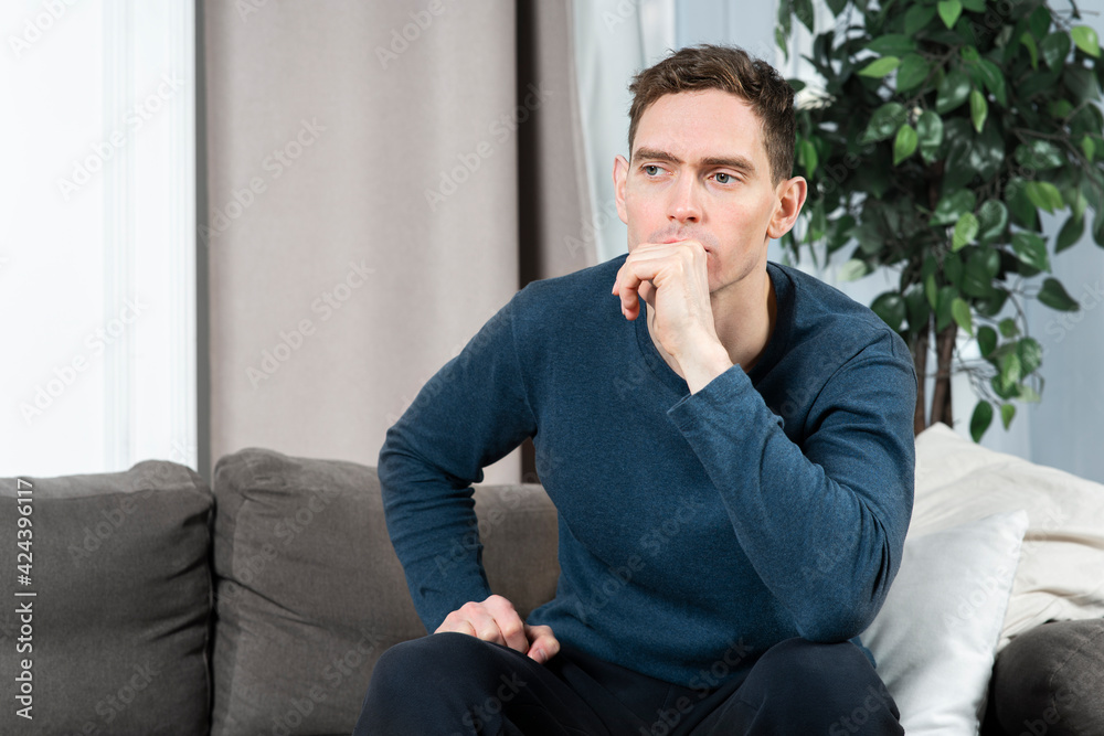 Portrait of sad upset depressed guy, young handsome frustrated pensive thoughtful lonely man with bored look is thinking, suffering from loneliness, boredom, sitting on couch or sofa at home Portrait of sad upset depressed guy, young handsome frustrated pensive thoughtful lonely man with bored look is thinking, suffering from loneliness, boredom, sitting on couch or sofa at home