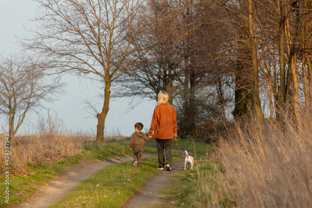 mother and son are walking along the countryside road at sunset mother and son are walking along the countryside road at sunset
