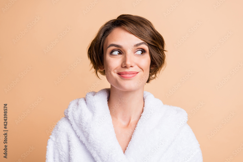 Photo of charming happy young woman wear bathrobe look empty space dream imagine isolated on pastel beige color background Photo of charming happy young woman wear bathrobe look empty space dream imagine isolated on pastel beige color background