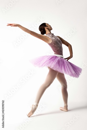 Japanese beautiful ballerina in pink tutu dancing on white background