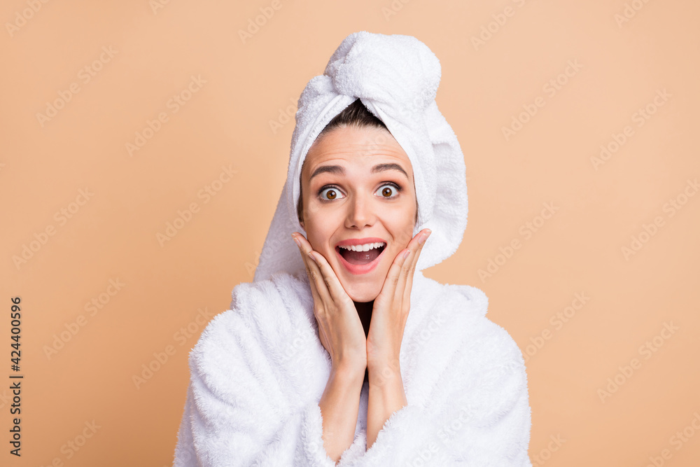 Photo of attractive amazed young woman hold hands cheekbones wear bathrobe isolated on beige color background Photo of attractive amazed young woman hold hands cheekbones wear bathrobe isolated on beige color background