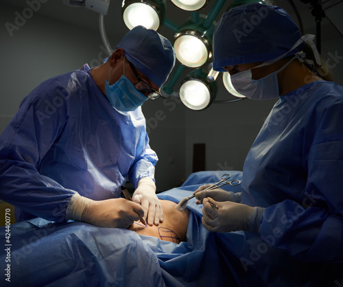 Surgeon and assistant doing plastic surgery in operating room.