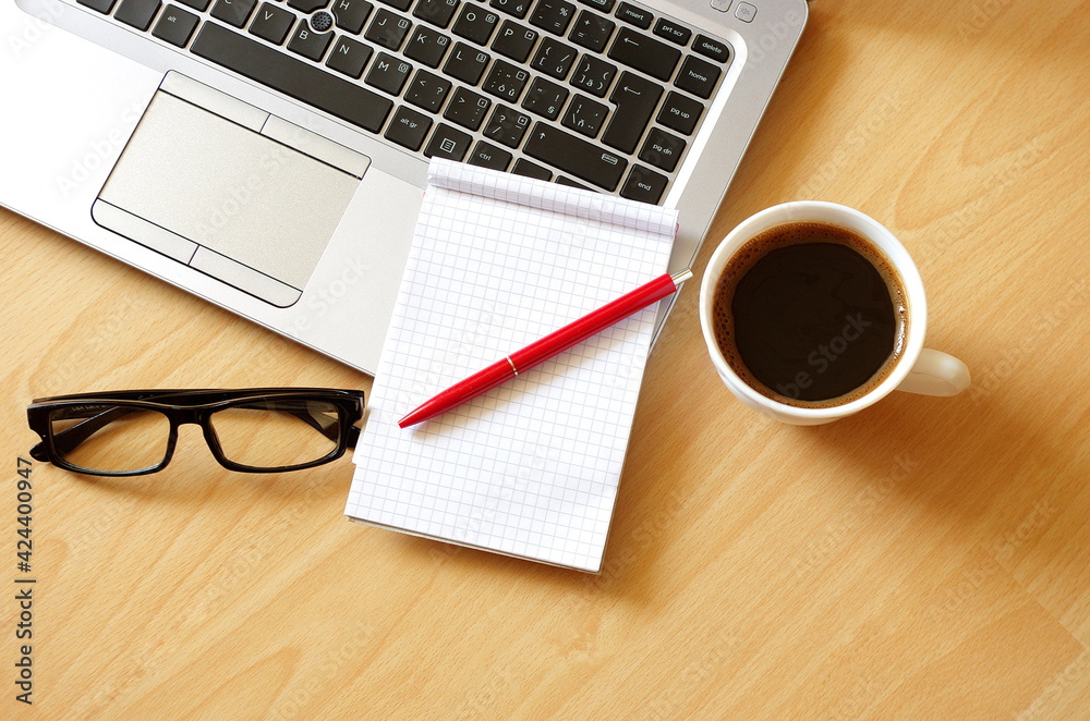 Laptop with coffee cup, notebook, glasses and pen on wooden background Top view. Concept for home office. Business concept. Work from home. Education background concept. Laptop with coffee cup, notebook, glasses and pen on wooden background Top view. Concept for home office. Business concept. Work from home. Education background concept.