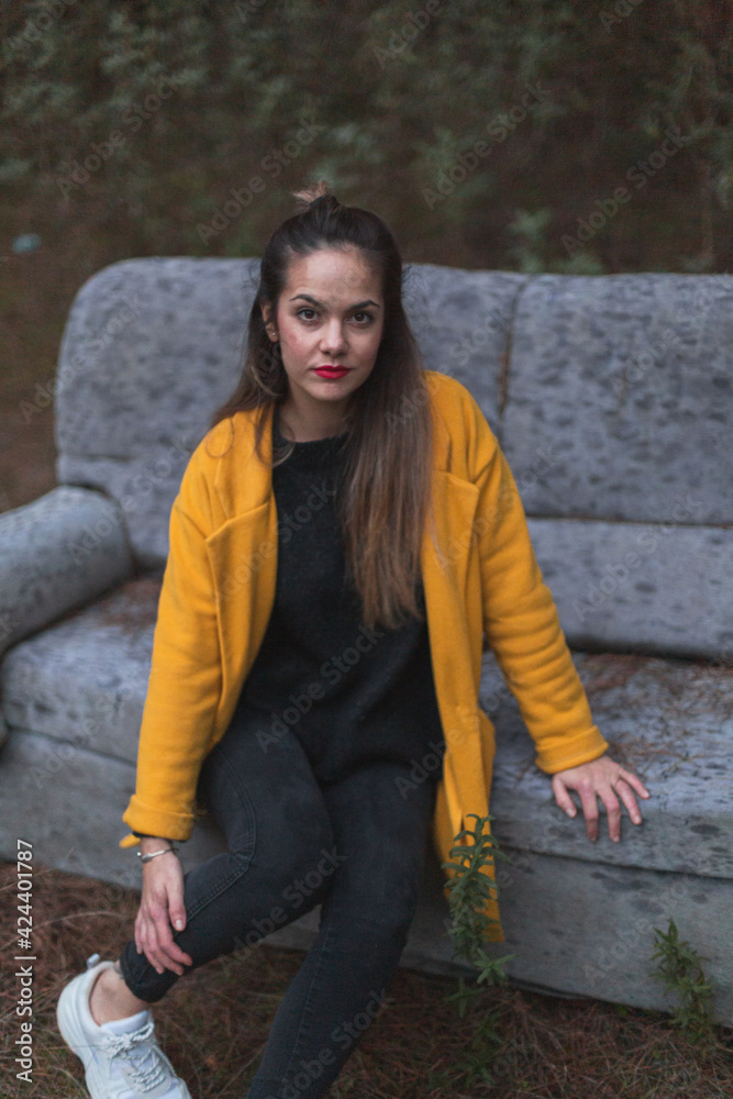 Beautiful woman sitting on a sofa wearing a yellow coat. Beautiful woman sitting on a sofa wearing a yellow coat.