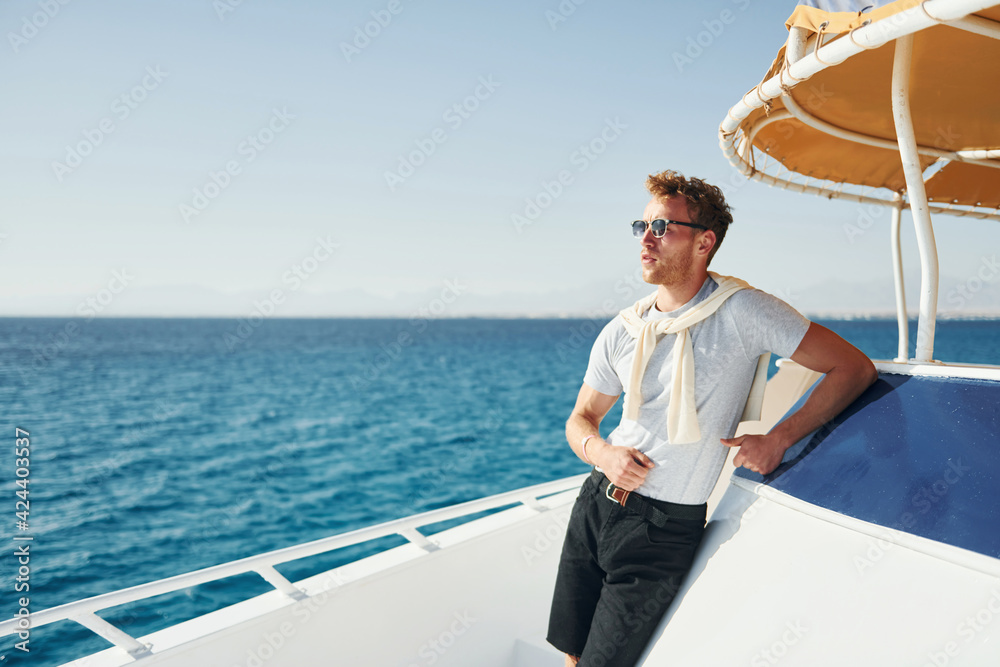 Young male tourist is on the yacht on the sea. Conception of vacation