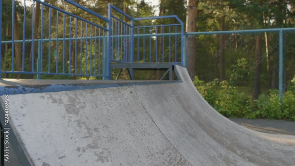 Slowmo low-section of unrecognizable young man skating and stalling on ramp in skateboard