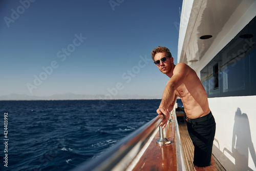 Warm weather. Young male tourist is on the yacht on the sea. Conception of vacation