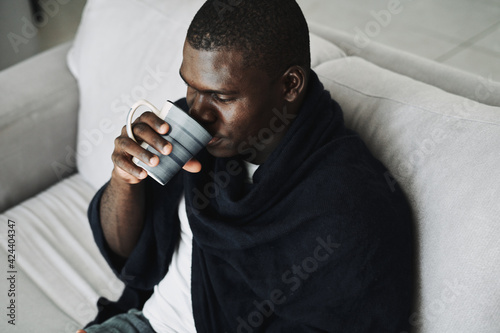 african-looking man drinking medicine at home health problems