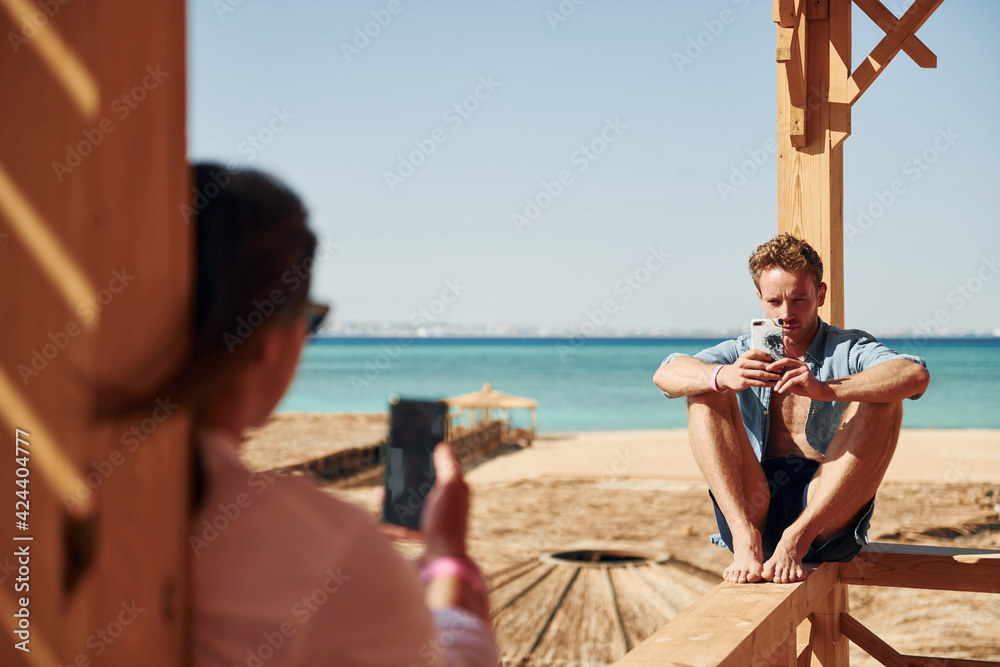 Young man and woman sitting on the beach of the sea. Conception of vacation