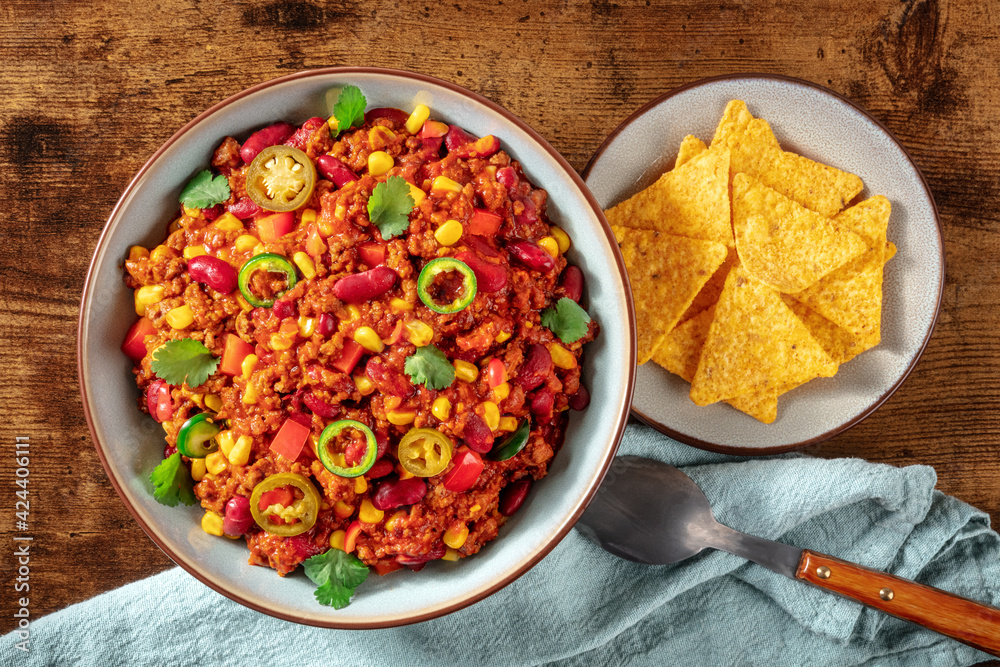 Chili con carne, spicy stew with beans and meat, shot from above with nachos Chili con carne, spicy stew with beans and meat, shot from above with nachos