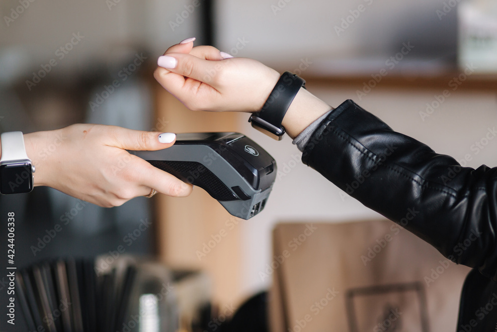 Female customer making wireless or contactless payment using smartwatch. Closeup of human hands during payment. Store worker accepting payment over nfc technology