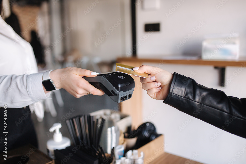 Female customer making wireless or contactless payment using credit card. Closeup of human hands during payment. Store worker accepting payment over nfc technology. Side view