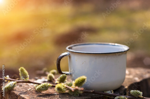 Enamel cup of coffee or tea, on a wooden board in a summer forest outdoors. Place for your text. 