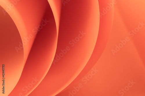 Abstract orange colored macro background  created with curved color paper sheets and macro photographing. Curved lines and shapes and soft vivid color.