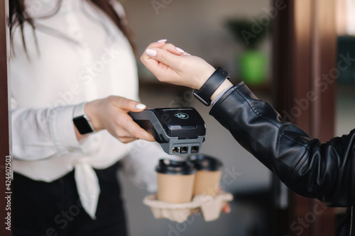 Female customer making wireless or contactless payment using smartwatch. Cashier accepting payment over nfc technology. Two people in face mask during quarantine. Covid19