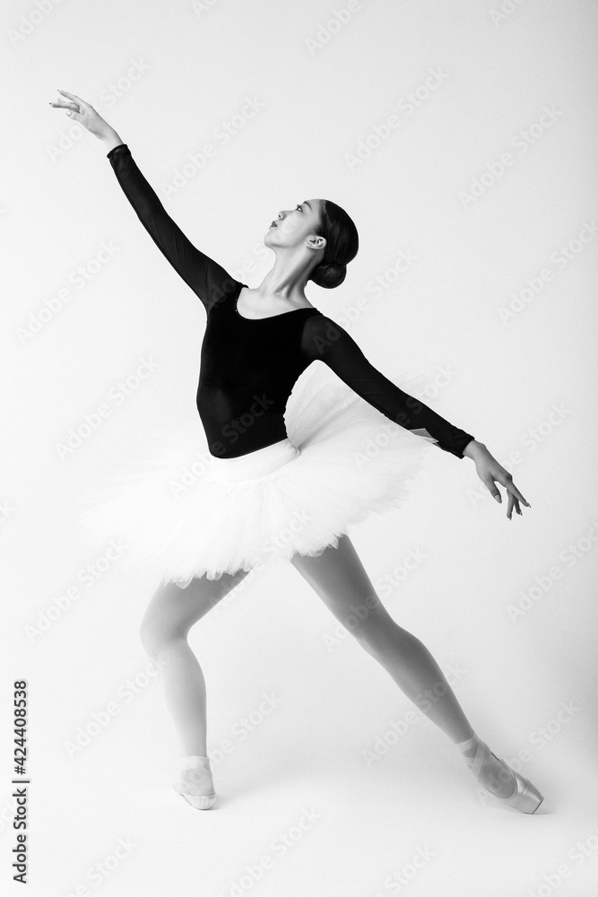 Graceful ballet dancer with black and white tutu in studio on white background