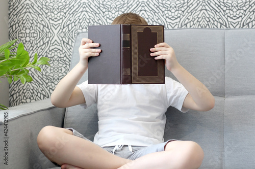 boy reading a book on the couch
 legs crossed. light photo in gray and white. close-up, no face visible