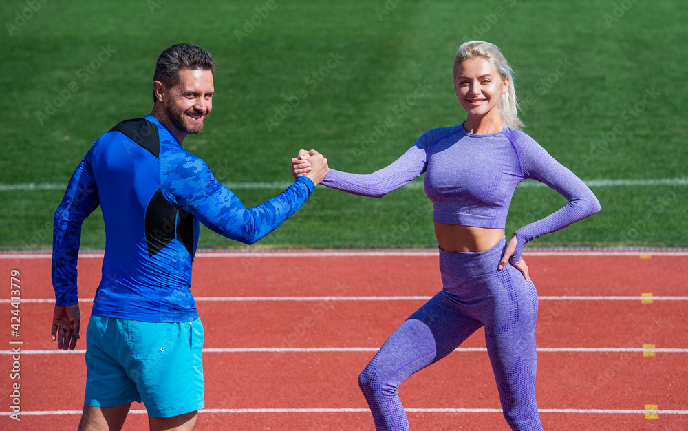 training with coach. fitness partners. athletic man and woman compete in armwrestling. male and female coach on stadium running track arena. healthy lifestyle. happy sport couple celebrate team win