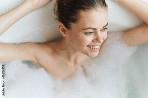 cheerful woman lies in the bathtub white foam clean skin health