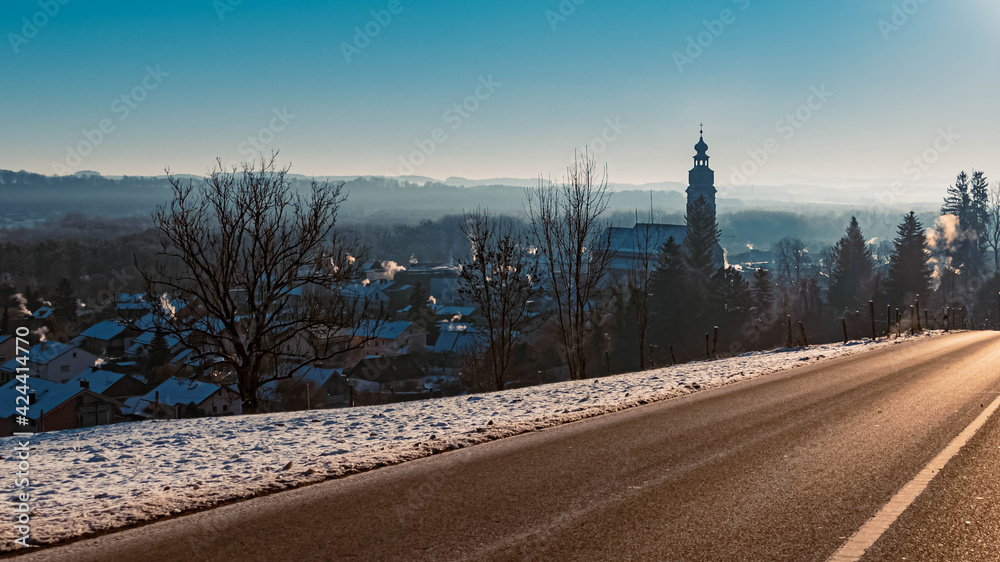 Beautiful hazy winter morning with a church and the famous Schafberg summit in the background at Tittmoning, Bavaria, Germany