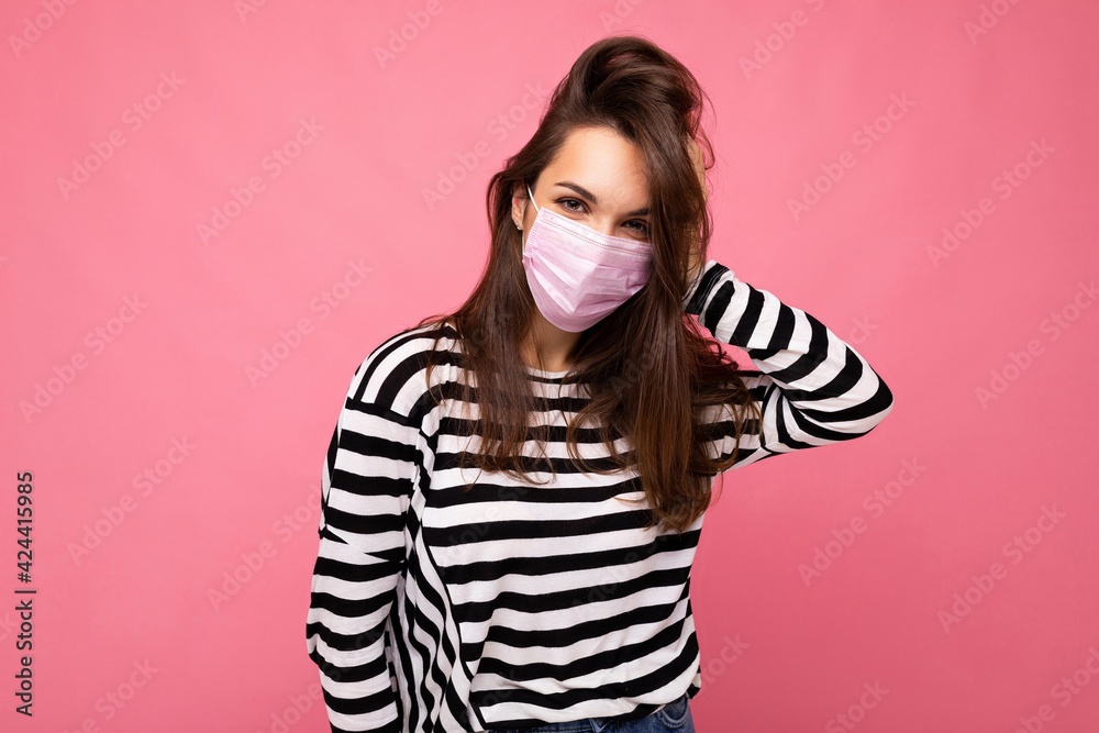 Fototapeta premium Shot of young attractive woman wearing mediacal face mask isolated over background wall. Protection against COVID-19