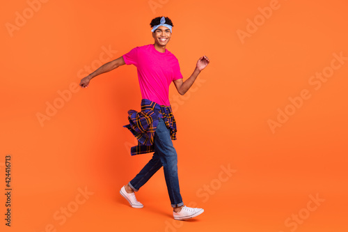 Full length photo of charming afro american young man go empty space wear shirt on waist isolated on orange color background