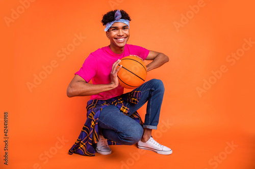 Full length body size photo guy sitting smiling keeping ball before training isolated vibrant orange color background