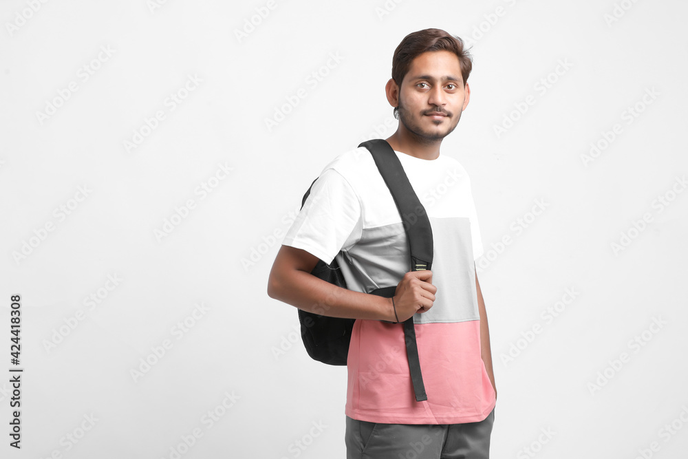 Handsome Indian college student carrying bag on white background.